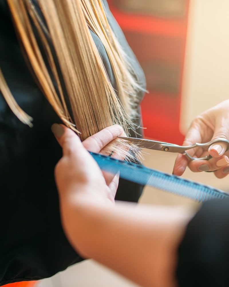 hairdresser-with-scissors-in-hand-cuts-female-hair-C32SN8Q-min.jpg
